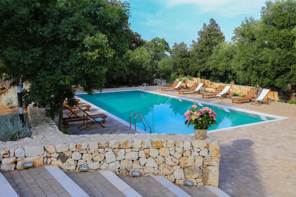 奥斯图尼Podere Madia的庭院旁的一座带石墙的游泳池