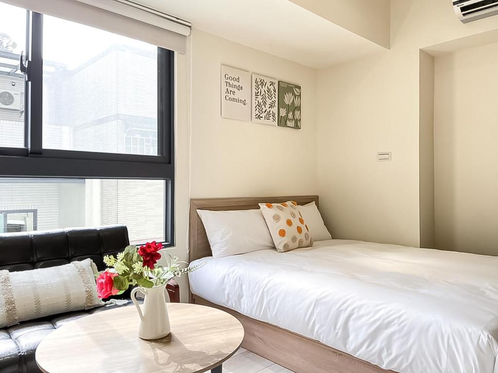 台中市旅行家 Affetto Hostel的一间卧室配有一张床、一张桌子和一张沙发