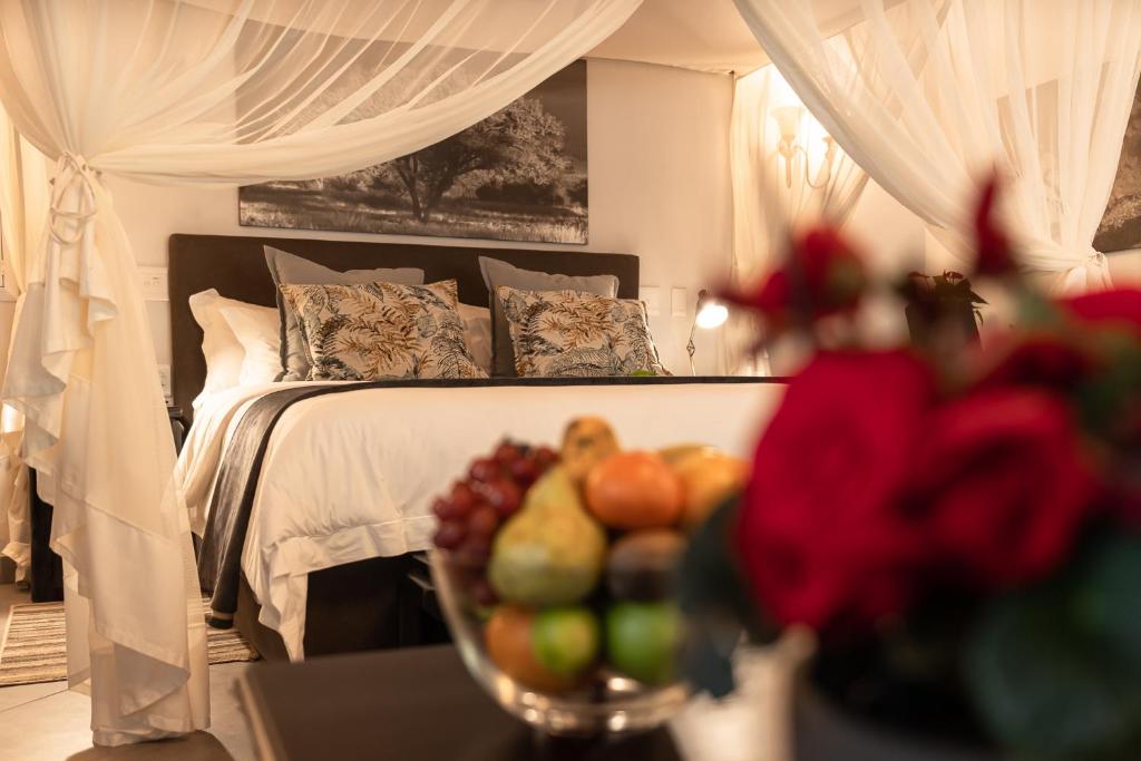玛洛斯帕克Kruger Eden Lodge的一间卧室,配有一张床上的床铺,桌上放着一碗水果