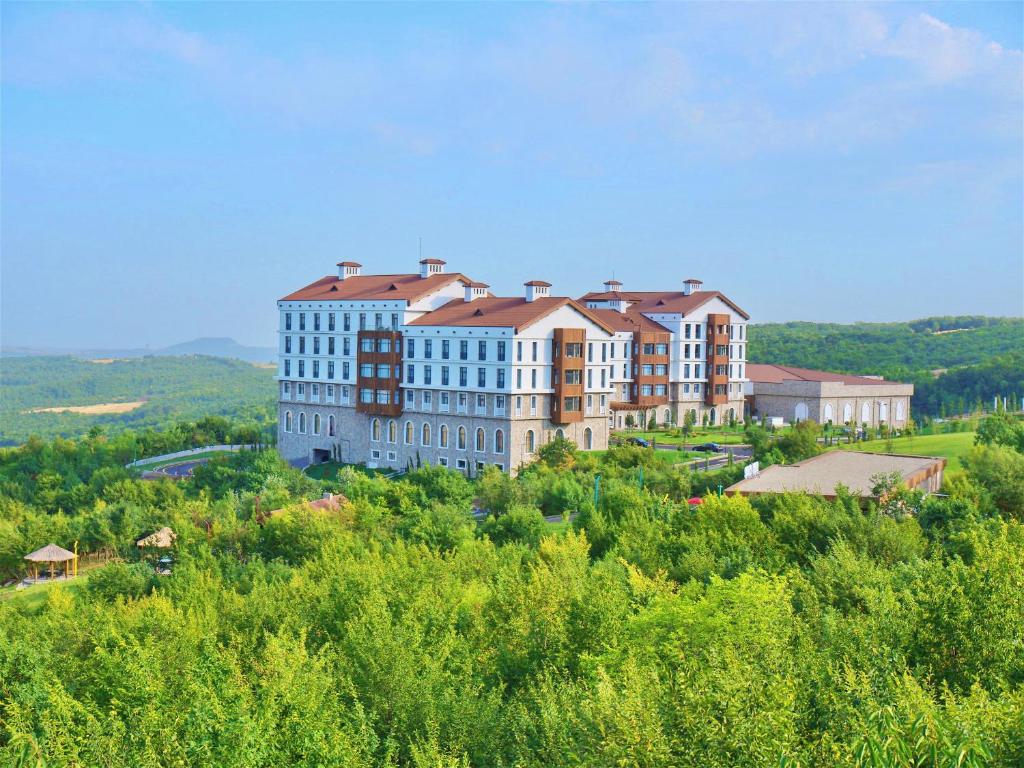 BasqalBasqal Resort & SPA的一座大建筑,位于一座树木繁茂的山顶上