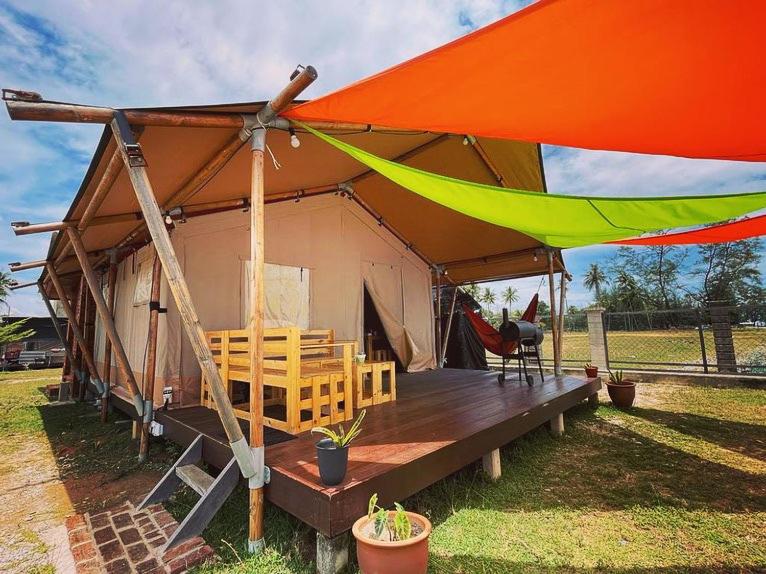 佩纳利克村Rembulan Escape - Beachfront safari tent的田野上带椅子和桌子的帐篷