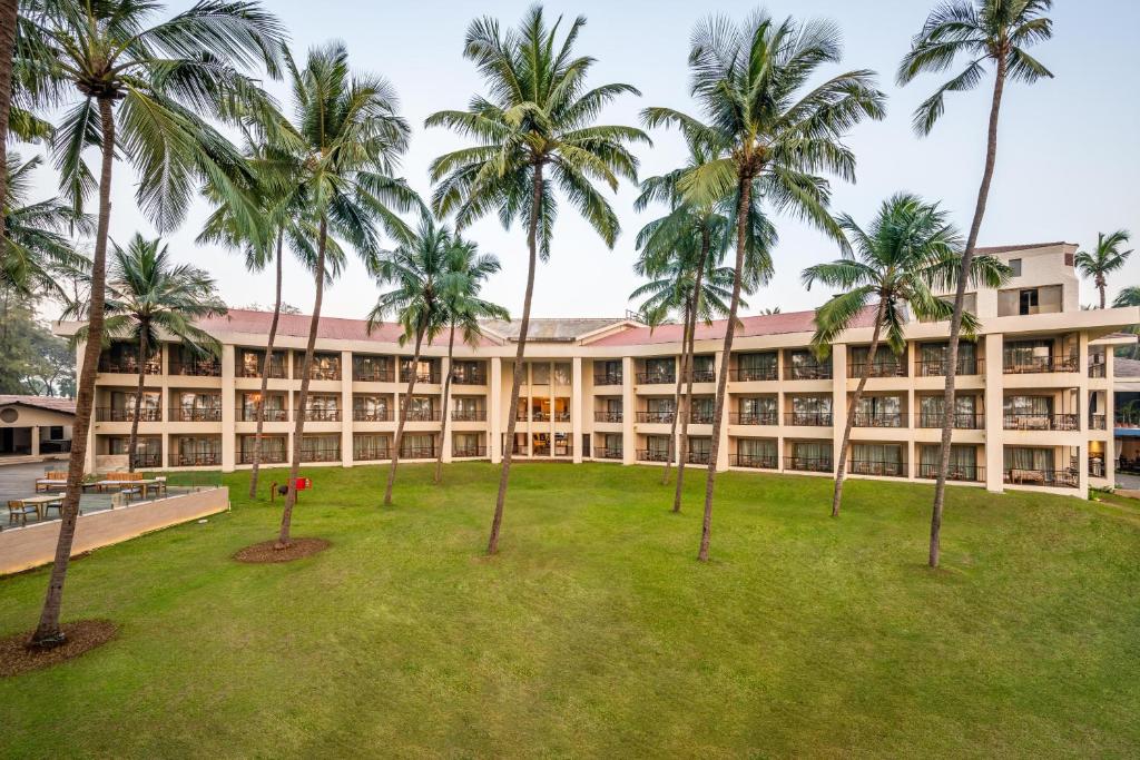 达曼Silver Waves Resort & Spa Daman, a member of Radisson Individuals的享有棕榈树建筑的外部景色