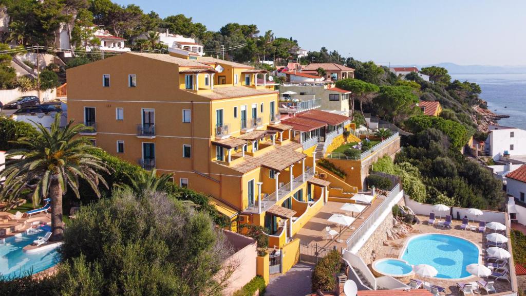 圣安蒂奥科Lu' Hotel Maladroxia的一座带游泳池的山丘上的大型黄色房屋