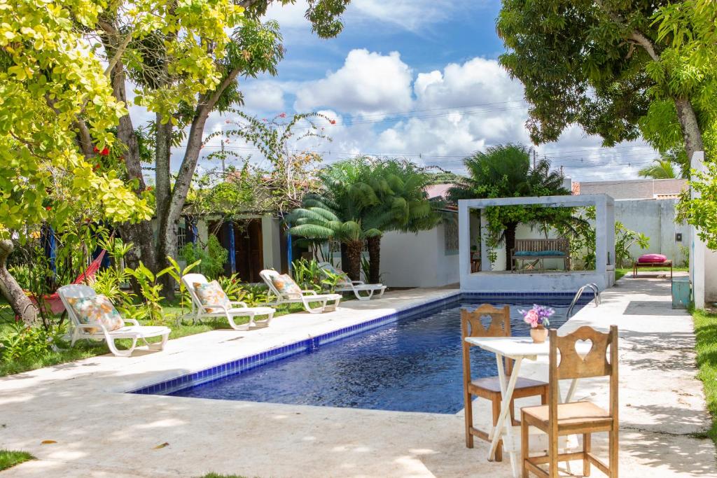 帕里普埃拉Villa Ostello Pousada的后院设有带椅子和桌子的游泳池