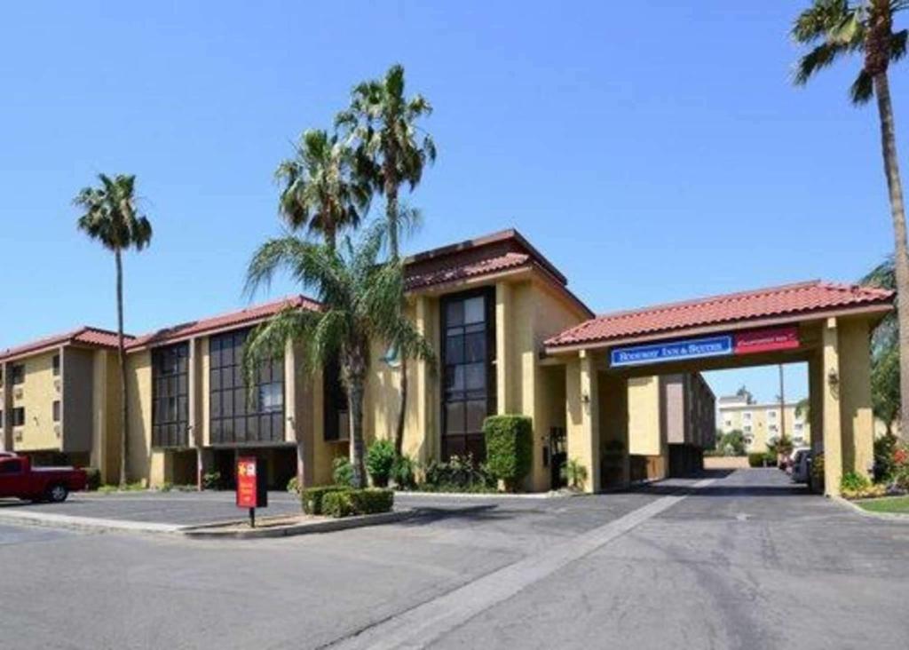 贝克斯菲尔德California Inn and Suites Bakersfield的街道前方有棕榈树的建筑
