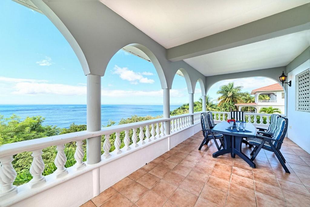 Méro加勒比海海景假日公寓的阳台配有桌椅,俯瞰着大海