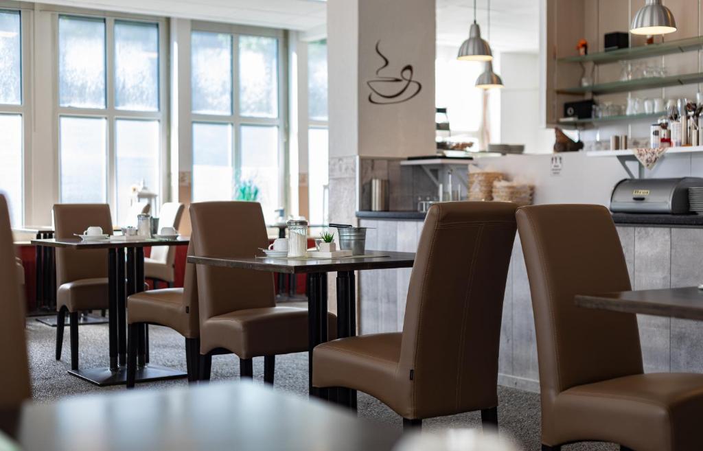 埃姆登库尔福厄斯特斯塔特长酒店的一间带桌椅的餐厅和一间厨房