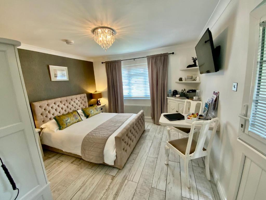 利明顿THE KNIGHTWOOD OAK a Luxury King Size En-Suite Space - LYMINGTON NEW FOREST with Totally Private Entrance - Key Box entry - Free Parking & Private Outdoor Seating Area - Town ,Shops , Pubs & Solent Way Walking Distance & Complimentary Breakfast Items的一间卧室配有一张床、一张书桌和一台电视