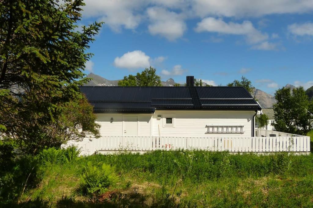 MefjordværCozy Apartment between sea and mountains的白色的房子,有黑色的屋顶和栅栏