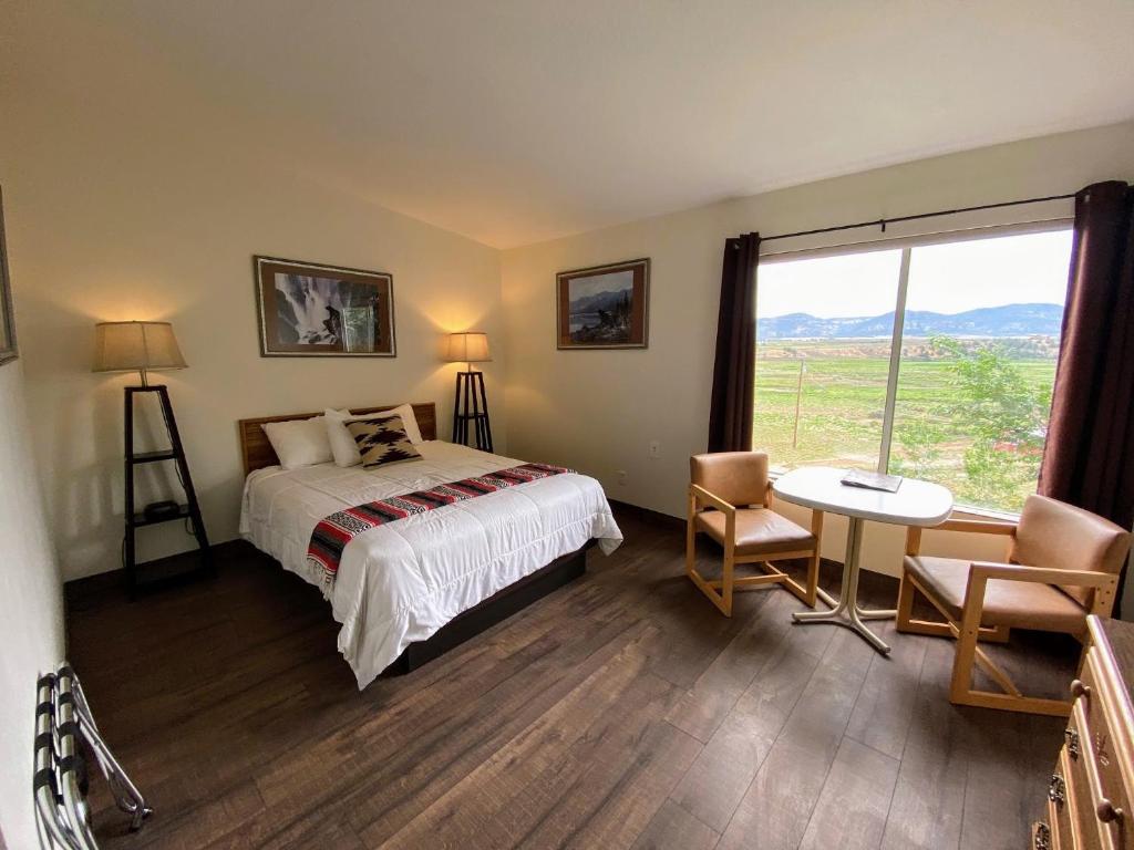 哈奇The Riverside Ranch Motel and RV Park Southern Utah的一间卧室配有一张床、一张桌子和一个窗户。