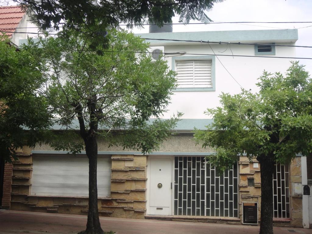 科尔多瓦Córdoba Alquila Alto Alberdi的一座带车库和两棵树的白色房子
