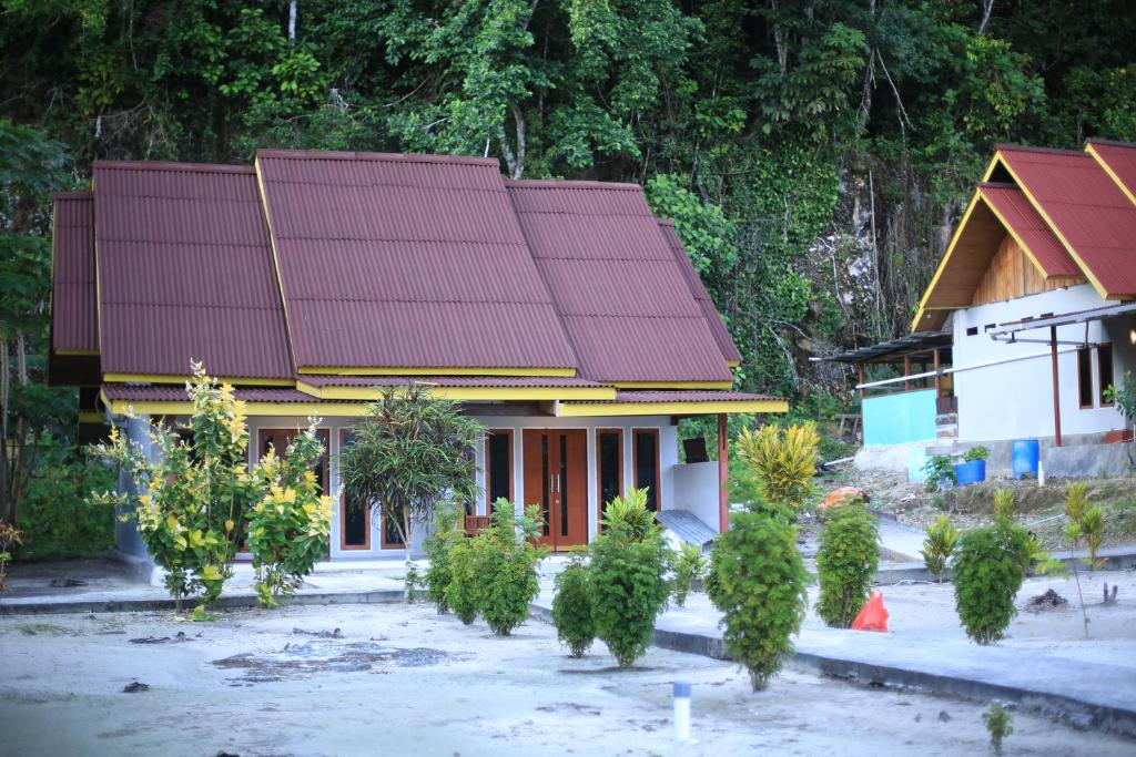 Pulau MansuarAmoryg Resort and Dive Raja Ampat的一座房子前面有红屋顶和树木