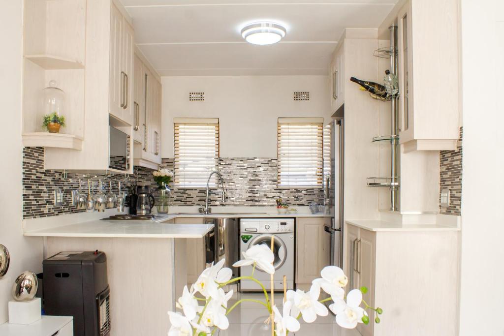 SandtonBeautiful 2 bedroom Apartment near Monte Casino的厨房配有白色橱柜和洗碗机。