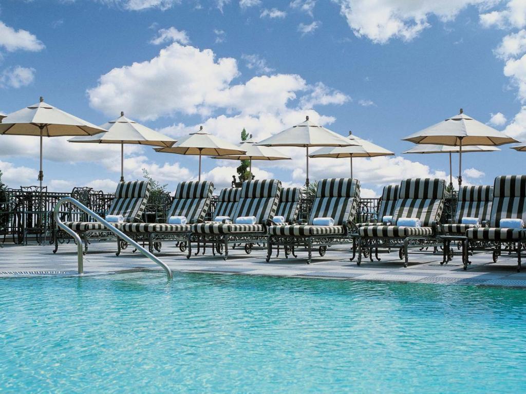 查尔斯顿市场廷苑酒店的一组椅子和遮阳伞,位于游泳池旁