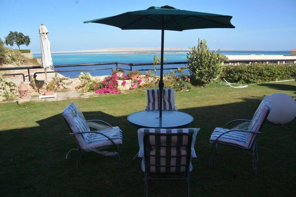 赫尔格达Prime Home The View Hurghada的一张桌子和椅子,配有雨伞和大海