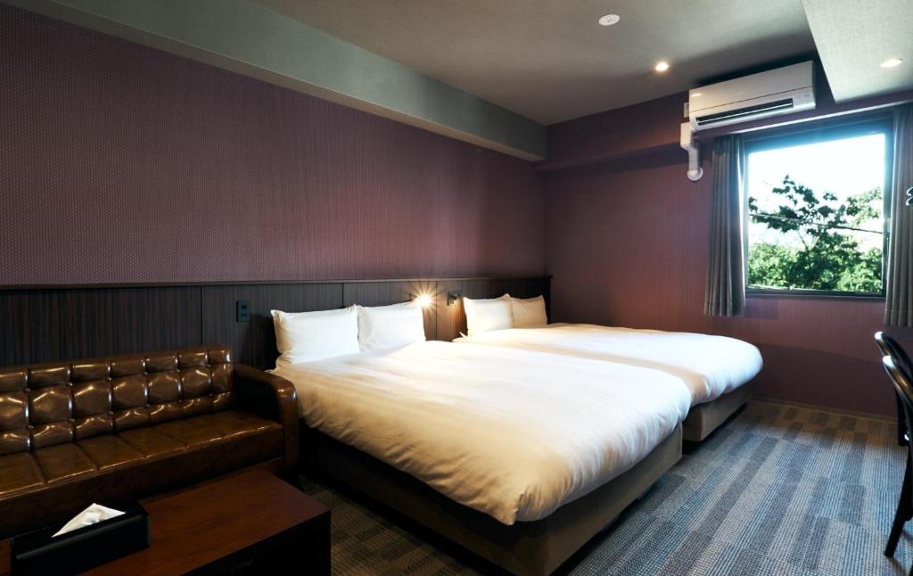 北九州Rakuten STAY Kokura Station Standard Twin Room with counter table的一间带两张床和一张沙发的卧室