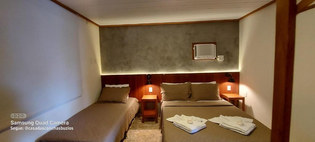 布希奥斯Casa das Conchas Búzios的配有两盏灯的小房间内的两张床