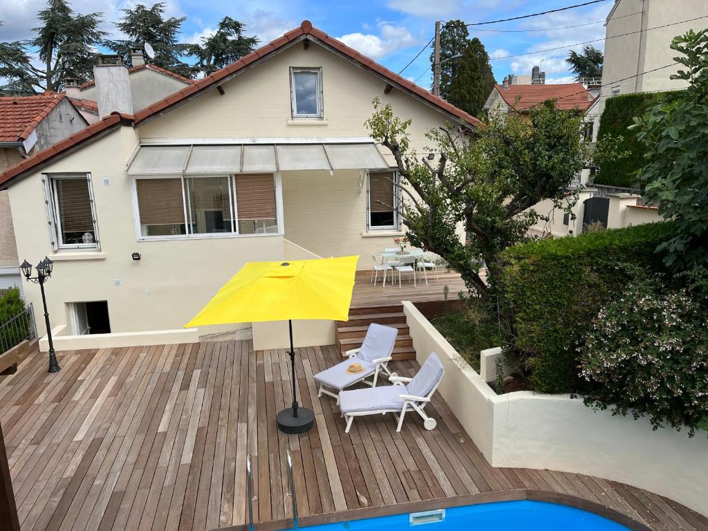 圣艾蒂安À la maison的木制甲板上的黄色遮阳伞和两把椅子