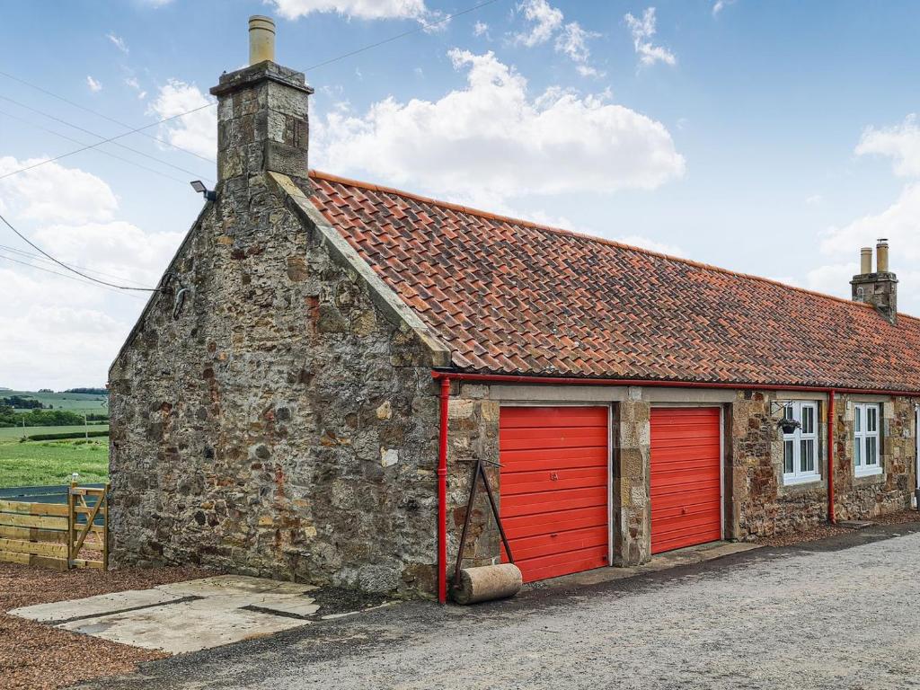 Longniddry2 Setonhill Cottages的一座古老的石头建筑,设有红色的车库门