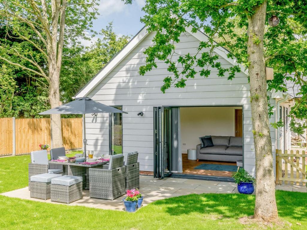 Stonham AspallWillow Cottage的后院庭院配有沙发和遮阳伞。