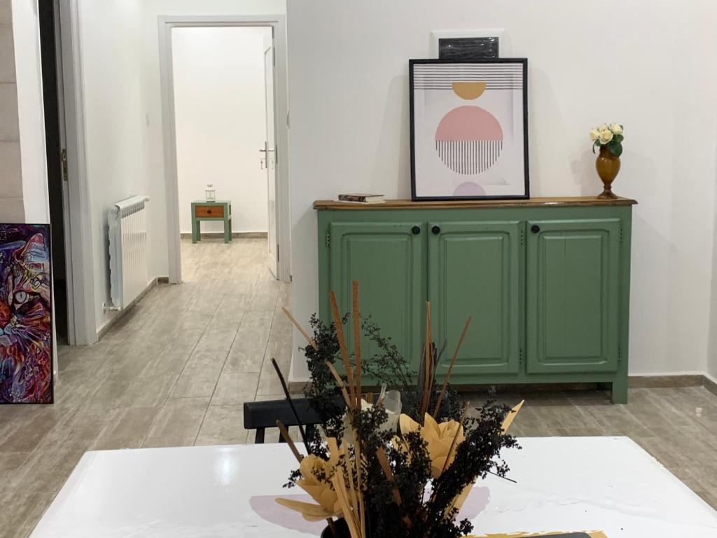 布米尔达斯Le Rocher的一间设有绿色橱柜和鲜花桌的房间