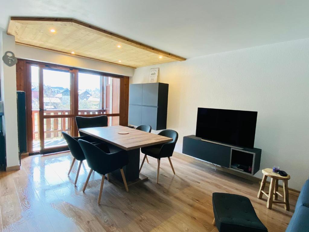 萨莫安斯Appartement en hyper centre de Samoëns的客厅配有桌椅和电视。