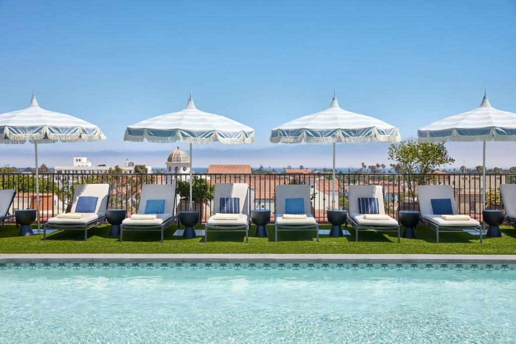 圣巴巴拉金普顿凯瑞酒店的一组椅子和遮阳伞,位于游泳池旁