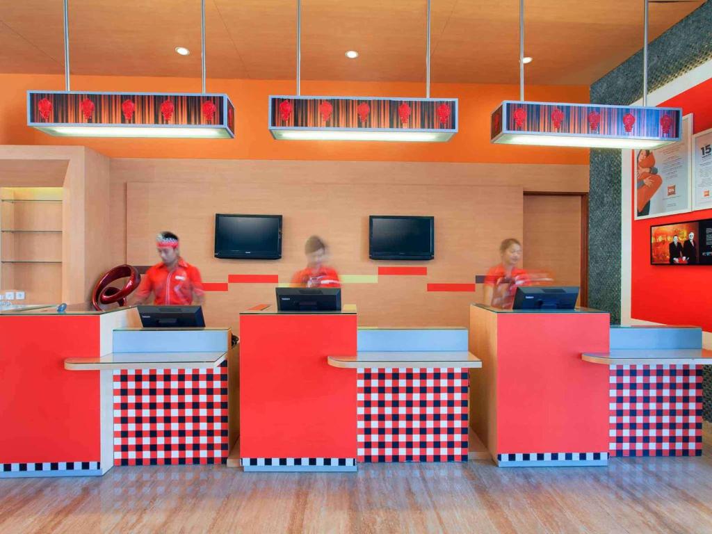 库塔巴厘岛库塔宜必思酒店的三人在一间设有红色柜台的快餐店