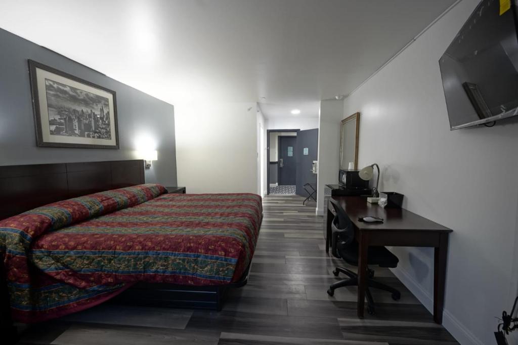 博林Greenwoods inn & Suites的一间卧室配有一张床、一张书桌和一台电视