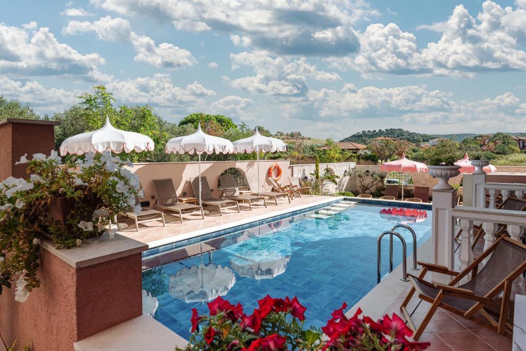 尼基季Kseynasa Suites的阳台的带椅子和遮阳伞的度假游泳池