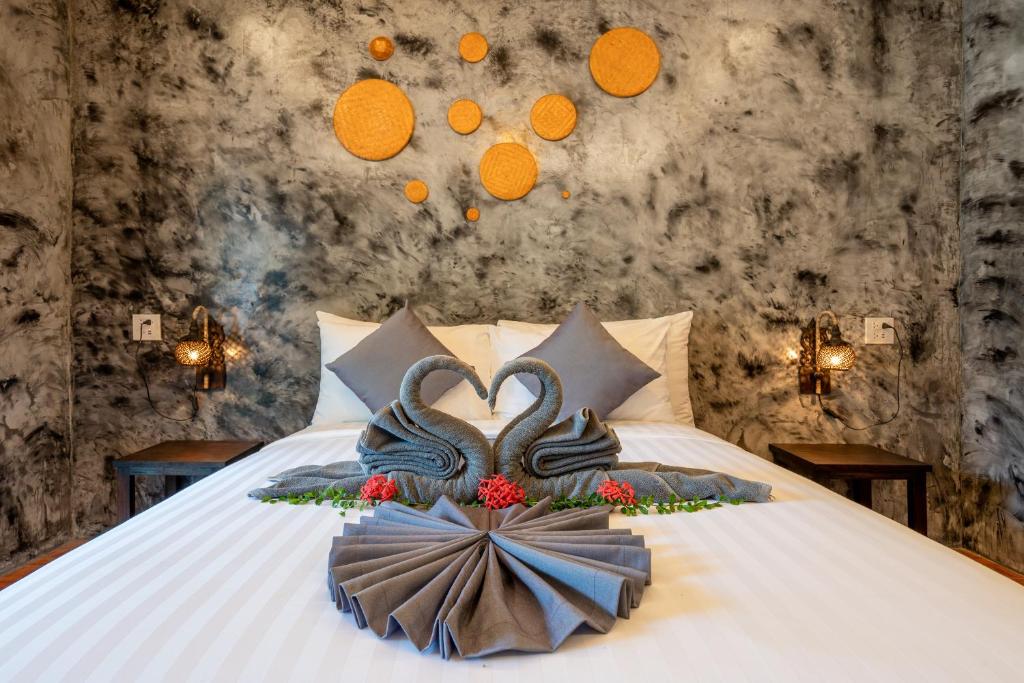 Phra Ae beachEl Matcha Lanta Resort的一张床上有两只天鹅在房间里