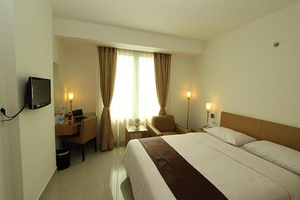 雅加达雅加达缇瑞尼缇酒店的一间卧室配有一张床、一张书桌和一个窗户。