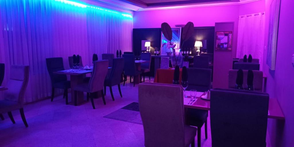 科托努L'Address的一间拥有紫色灯光和桌椅的用餐室