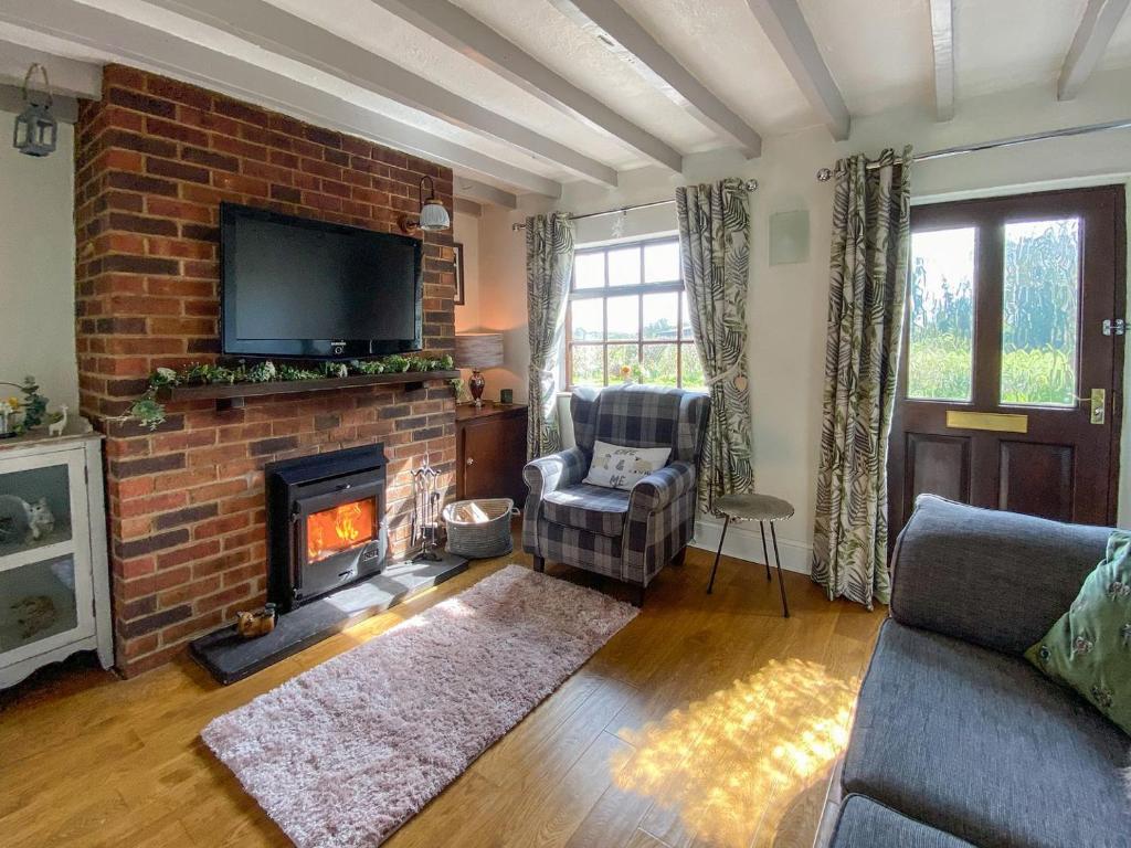 ShardlowWilne Cottage的客厅设有砖砌壁炉和电视。