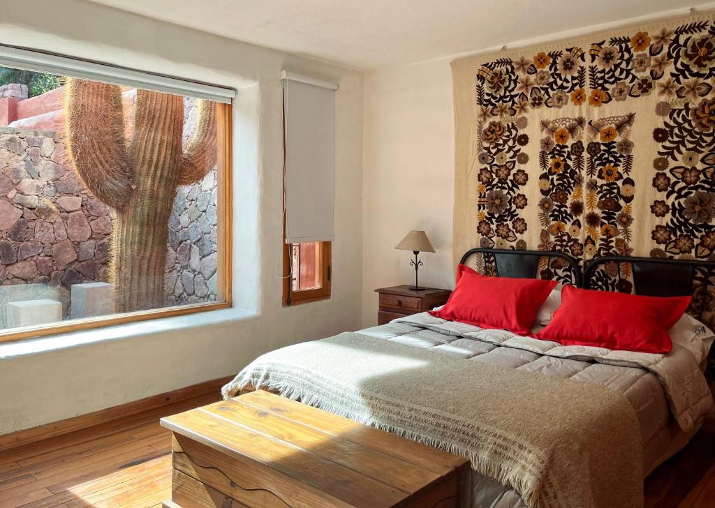 普尔马马尔卡Chilcagua的一间卧室配有一张带红色枕头的床和一扇窗户