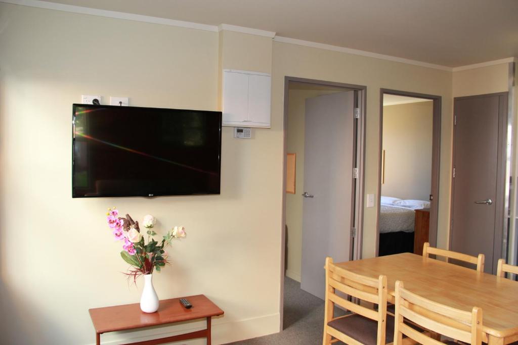 纳尔逊尼考公寓酒店的一间设有桌子和墙上电视的用餐室