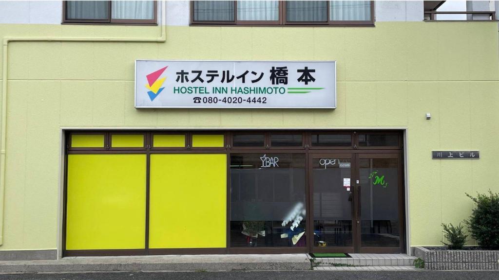桥本Hostel Inn Hashimoto的大楼内有黄色门和标志的商店