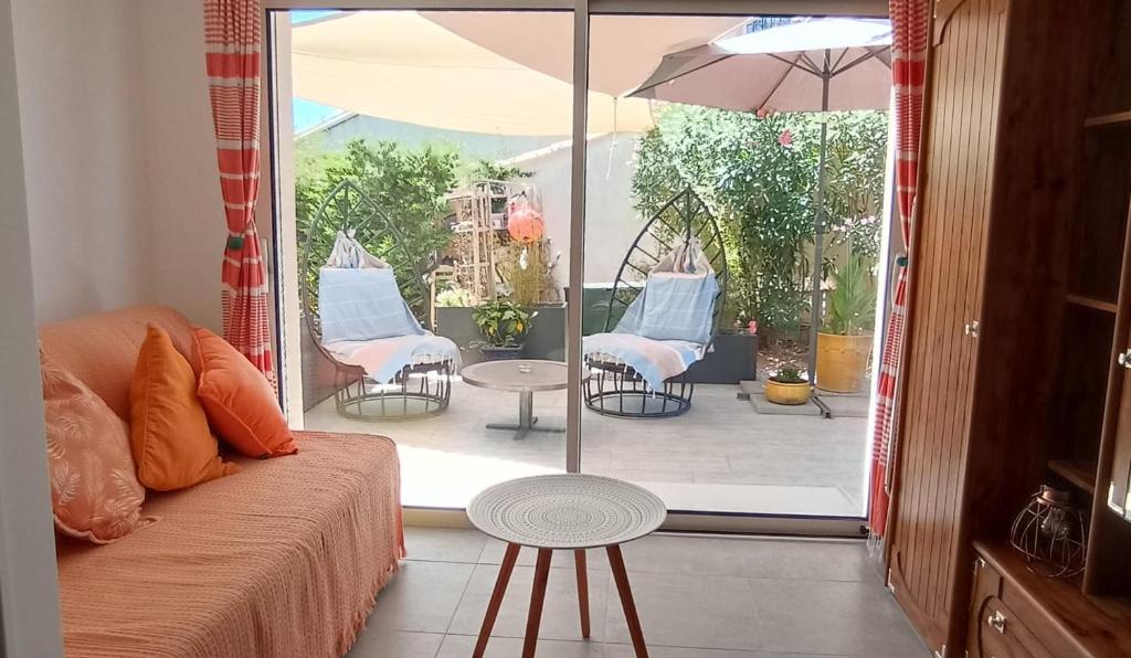 布齐盖Escale à Bouzigues的带沙发的客房以及带椅子和遮阳伞的天井。