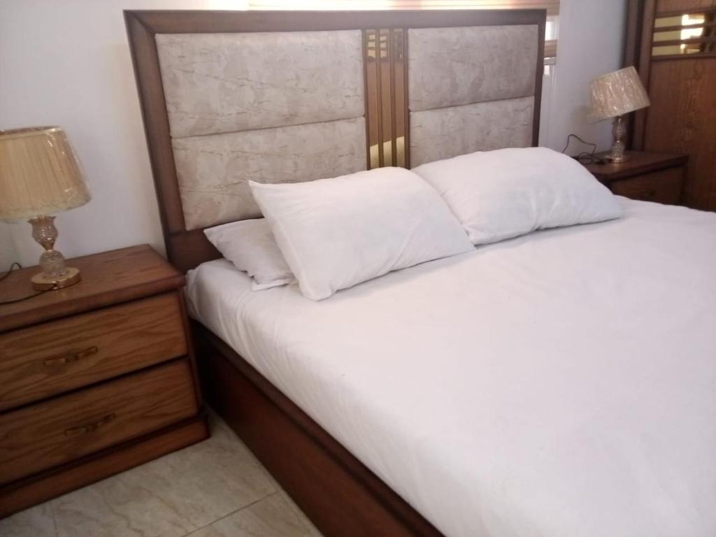 杰拉什Furnished apartment for rent in jarash شقة مفروشة للإيجار في جرش的一间卧室配有一张带白色床单的床和床头柜。