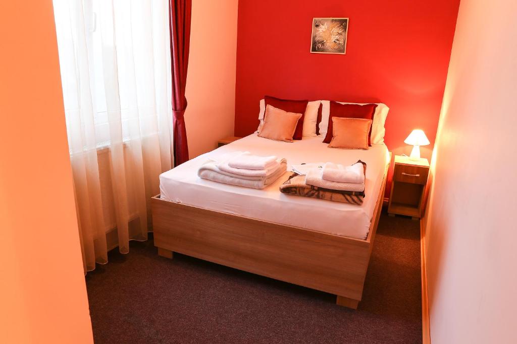 米特罗维察Hotel North City的一间小卧室,配有一张红色墙壁的床