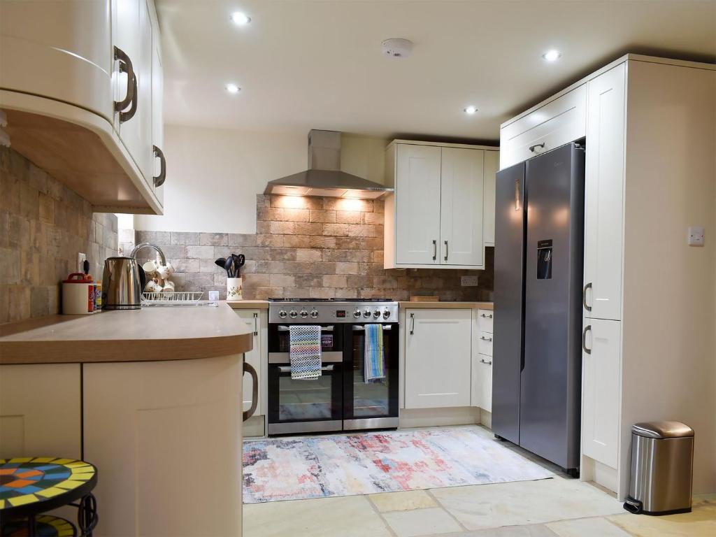 Stannington2 The Calf Pens的厨房配有白色橱柜和不锈钢冰箱