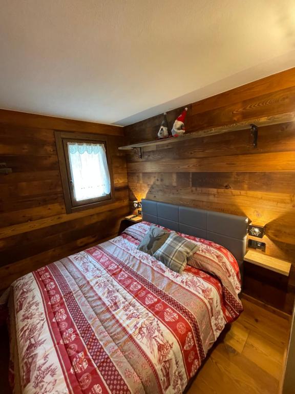 布勒伊-切尔维尼亚Baita del Cervino CIR n 0016的一间卧室配有一张带木墙和窗户的床。