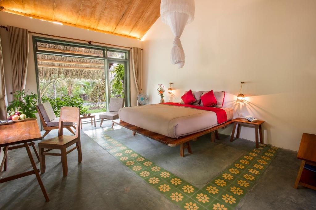槟知湄公河之家民宿 的卧室配有一张床和一张桌子及椅子