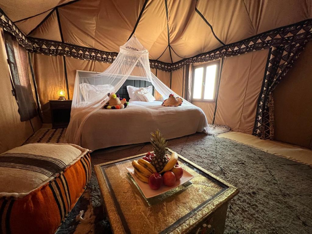 梅尔祖卡Luxury traditional Tent Camp的帐篷里的卧室配有一张床,备有水果盘