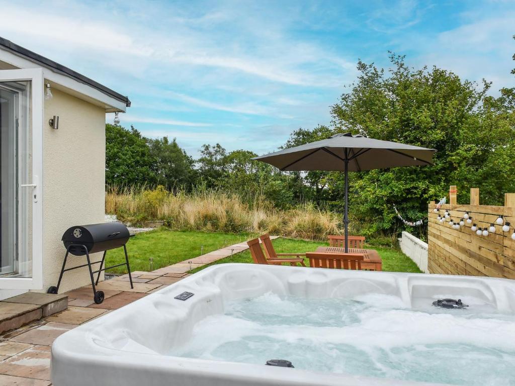 BrynammanHighfield Bungalow的后院的热水浴池,配有遮阳伞
