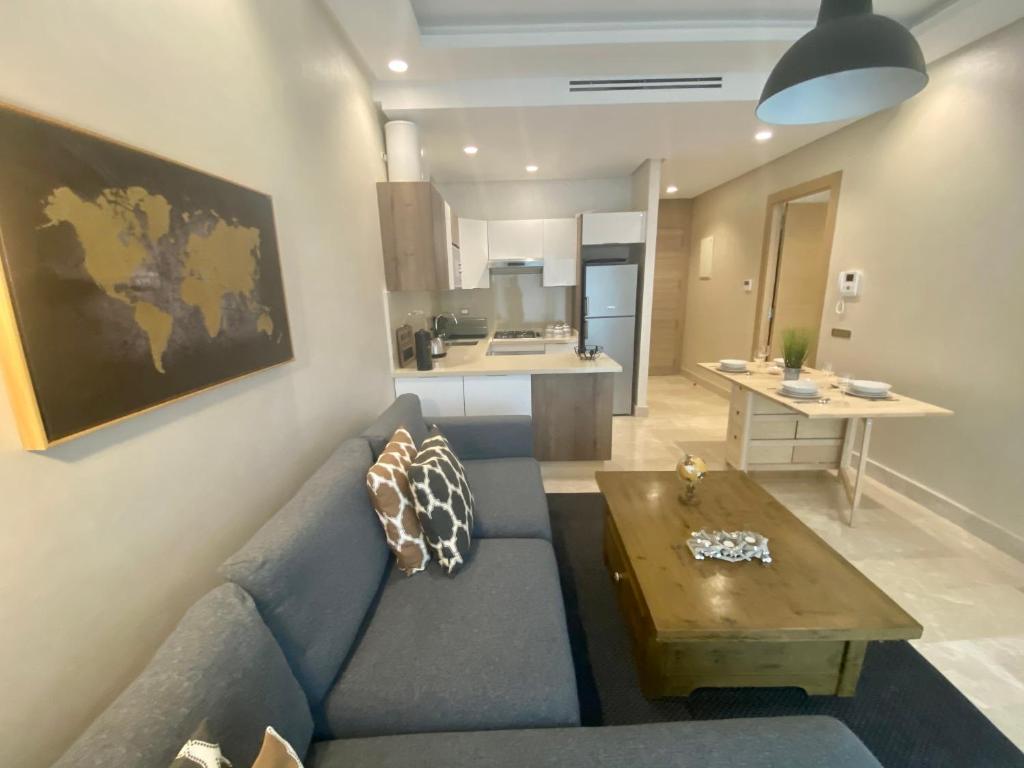 卡萨布兰卡Appartement confortable et ensoleillé, belle vue的客厅配有蓝色的沙发和木桌