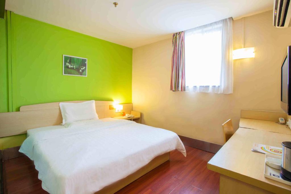 贵阳7天连锁酒店贵阳延安西路店的卧室配有白色的床和绿色的墙壁