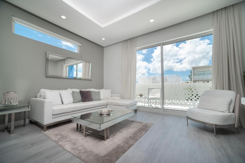 Upper LandLuxury 1 bed apartment near Seven Mile Beach at The Grove - Villa Deluxe的客厅配有白色家具和大窗户