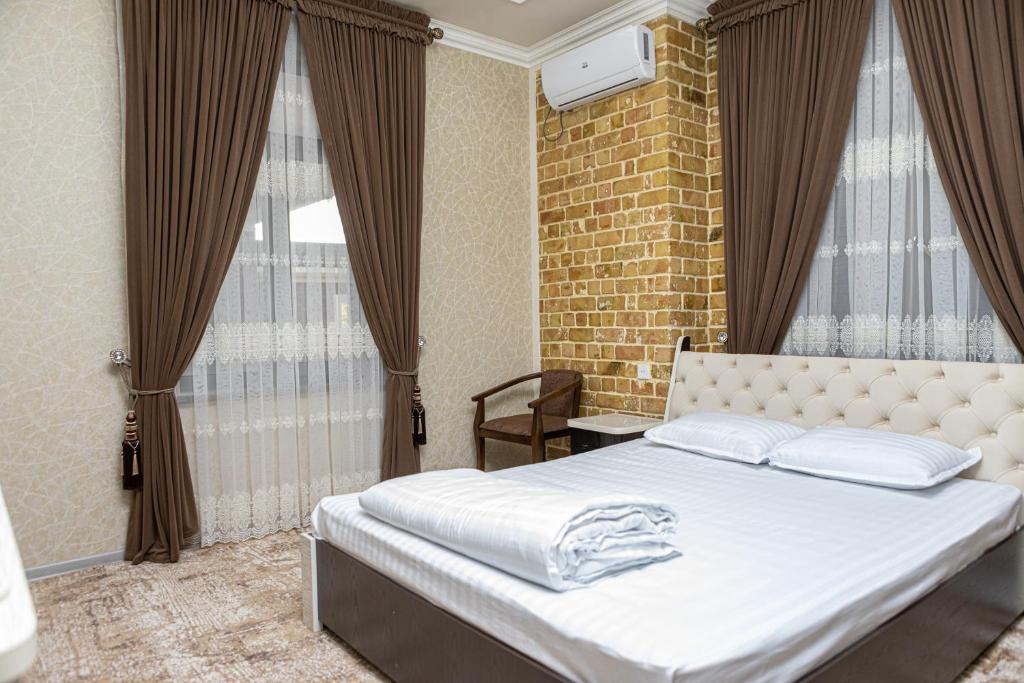 撒马尔罕AHMAD HOTEL的卧室配有白色的砖墙床