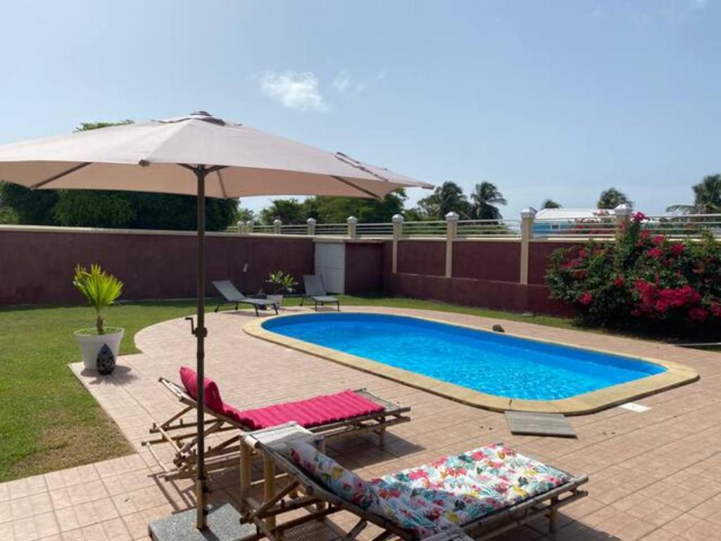 圣弗朗索瓦Appartement cosy & calme en Rez de villa的一个带2把躺椅和遮阳伞的游泳池